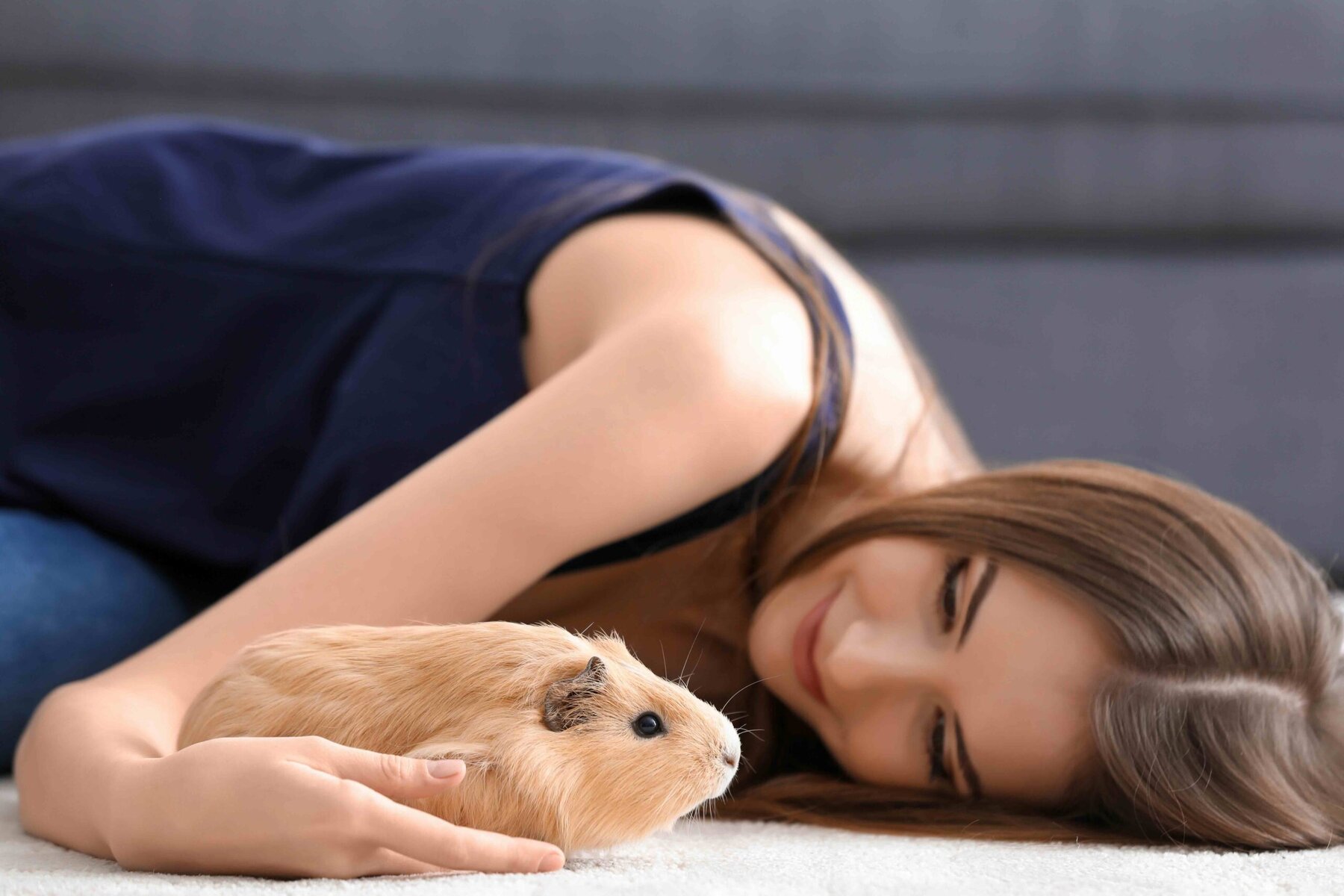 Beautiful young woman with pet guinea pig at home